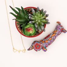 Load image into Gallery viewer, Gold tone necklace with open heart and paws connected by a heartbeat rhythm. Diplayed on white background with mosaic dachsund figurine and succulent plant. .