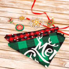 Load image into Gallery viewer, Picture of two Christmas pet bandanas. Bandana 1 (front in picture) has a green and black buffalo plaid check pattern with Merry Christmas printed on it. Bandana 2 has a red and black check pattern with white snowflake images superimposed. Displayed on wooden board with red ribbon and Christmas ornament cut-outs.