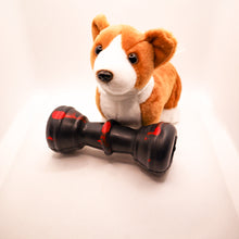 Load image into Gallery viewer, Angled view picture of Dogzilla Strong Chewer Bone dog toy. Bone is hard black rubber with red accents. Displayed on a white background with a stuffed corgi toy.
