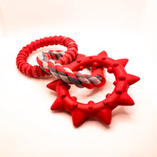 Load image into Gallery viewer, Side view picture of Dogzilla Dino Links dog toy.  Toy has two hard red rubber rings connected by a twisted red/light gray/dark gray rope ring.  One hard rubber ring has ridges for texture.  The second rubber ring has pointed spikes.  Displayed on a white background. 
