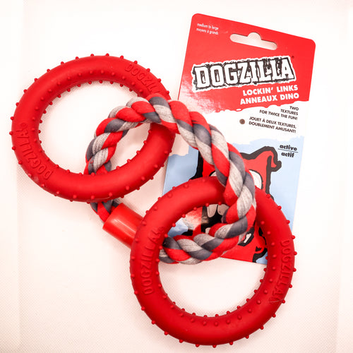 Overhead view picture of Dogzilla Lockin' Links dog toy. Toy has two hard red rubber rings connected by a twisted red/light gray/dark gray rope ring. Both hard rubber rings have raised nubs for texture. Displayed on a white background with card tag. 