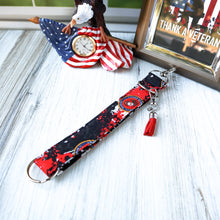 Load image into Gallery viewer, Marine Charmable Wristlet keychain on white wood with an eagle clock and picture in the background. 

