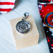 Load image into Gallery viewer, closeup of the Marine Seal charm on a light wood block with a flag and Marine Charmable keychain in the background. 

